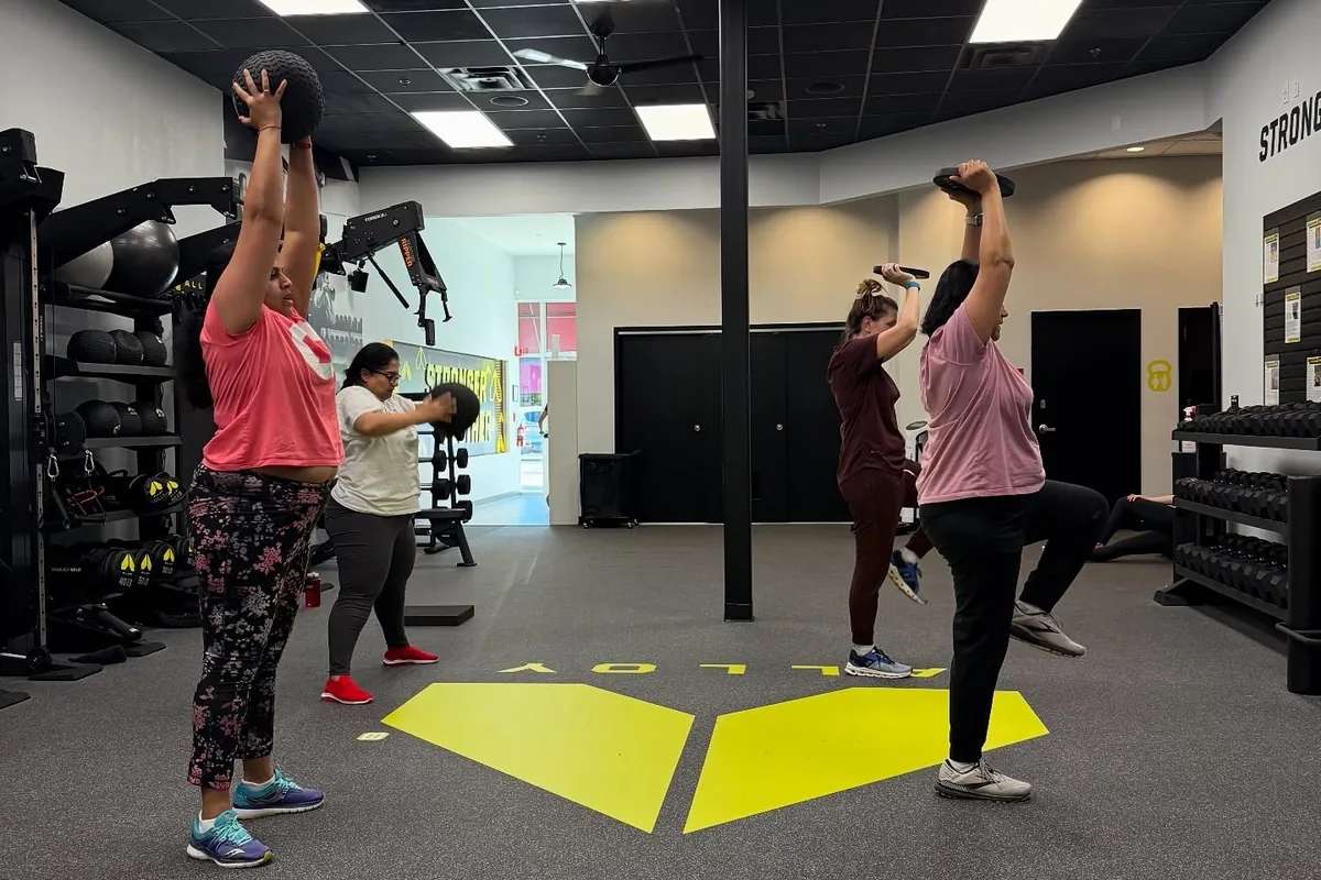 Members strength training with coach supervision at Alloy Personal Training Cary